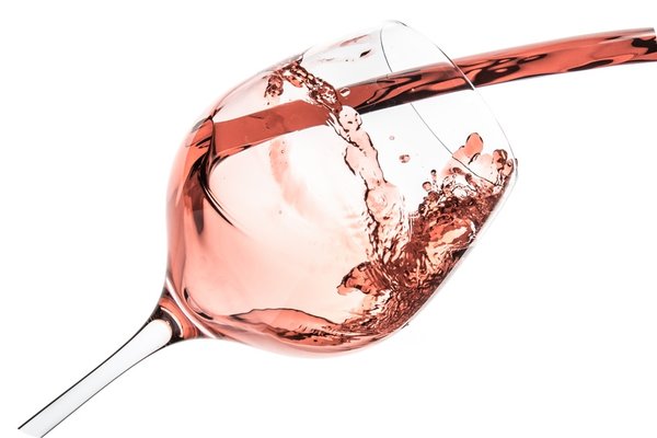 Bild von einem Weinglas, in welches Rosé Wein gegossen wird.